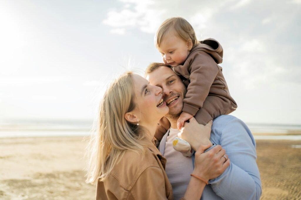 Gelukkig gezin geniet van een stranddag, met peuter op de schouders van vader, die een moment van vreugde deelt.