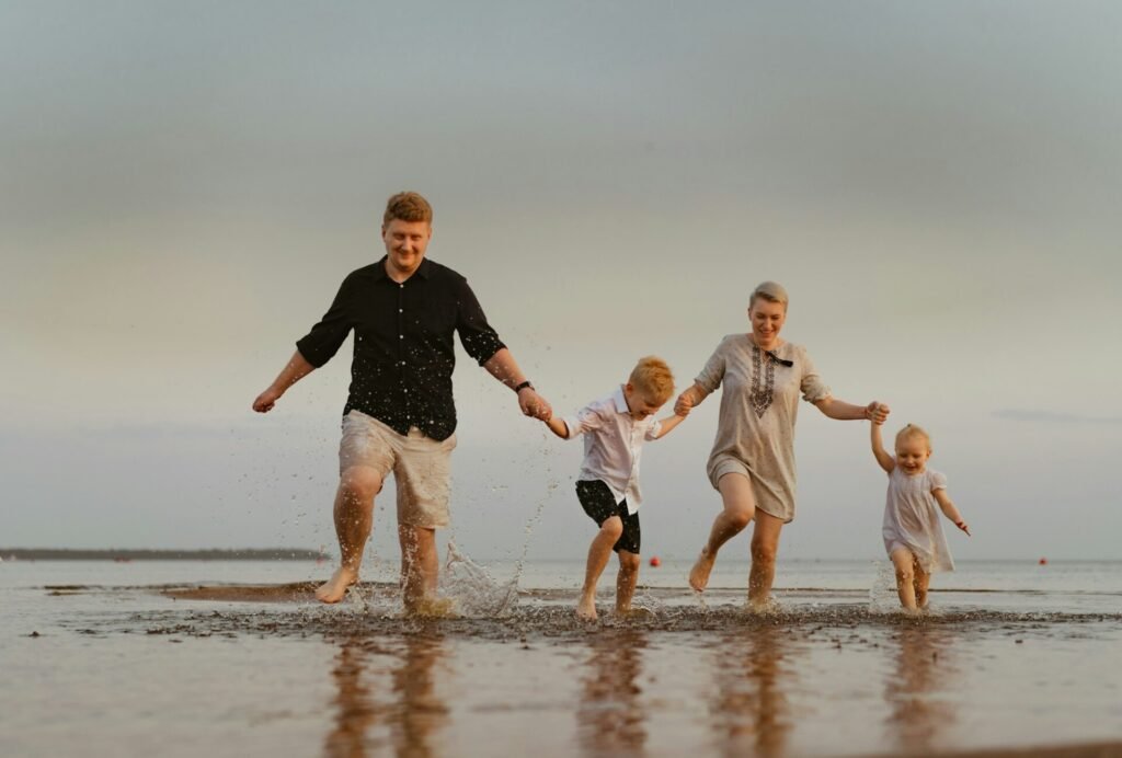 famille caucasienne s'amusant à courir dans la mer au coucher du soleil.