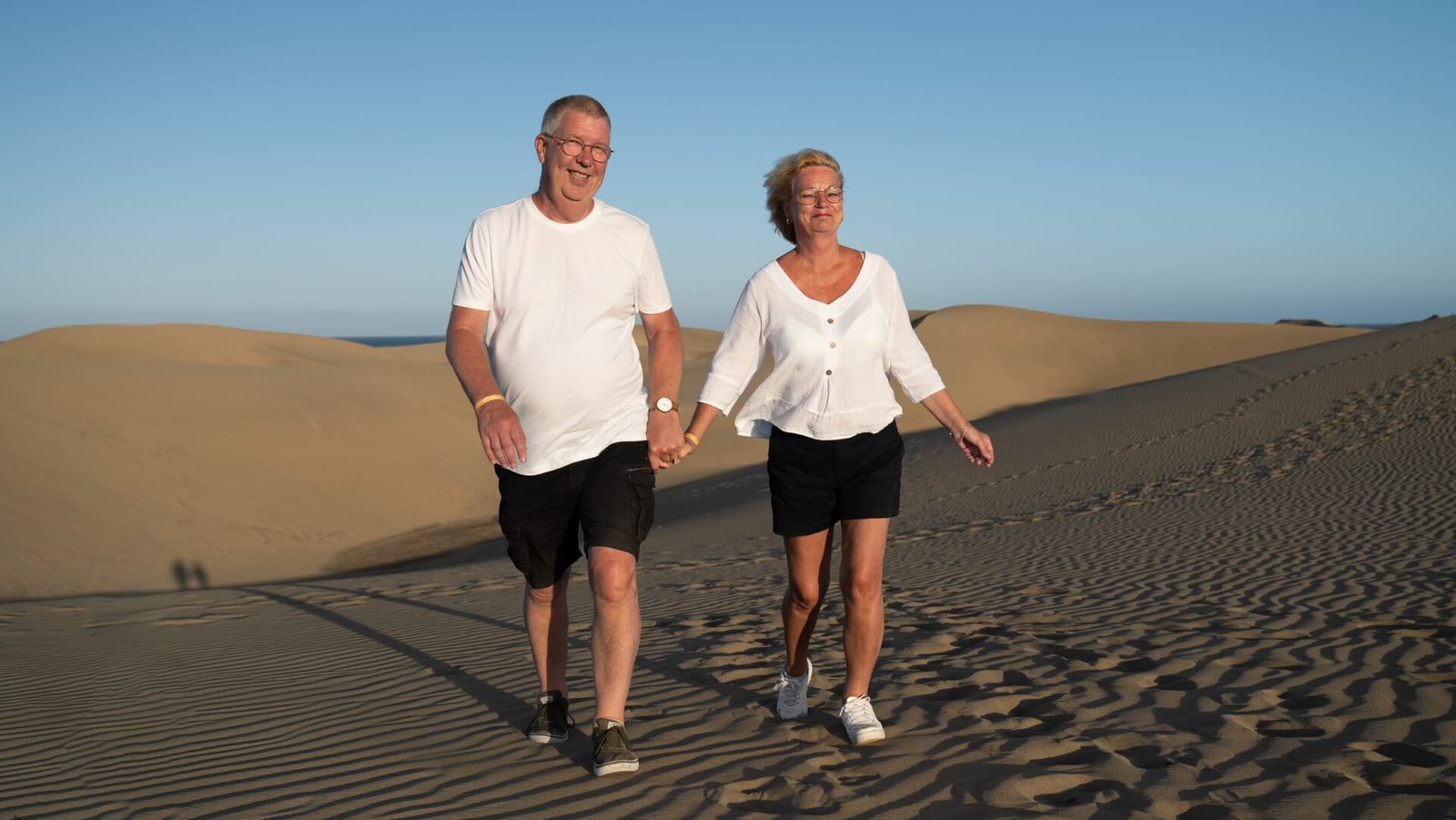 Casual couple with glasses laughing on the dunes Gran Canaria