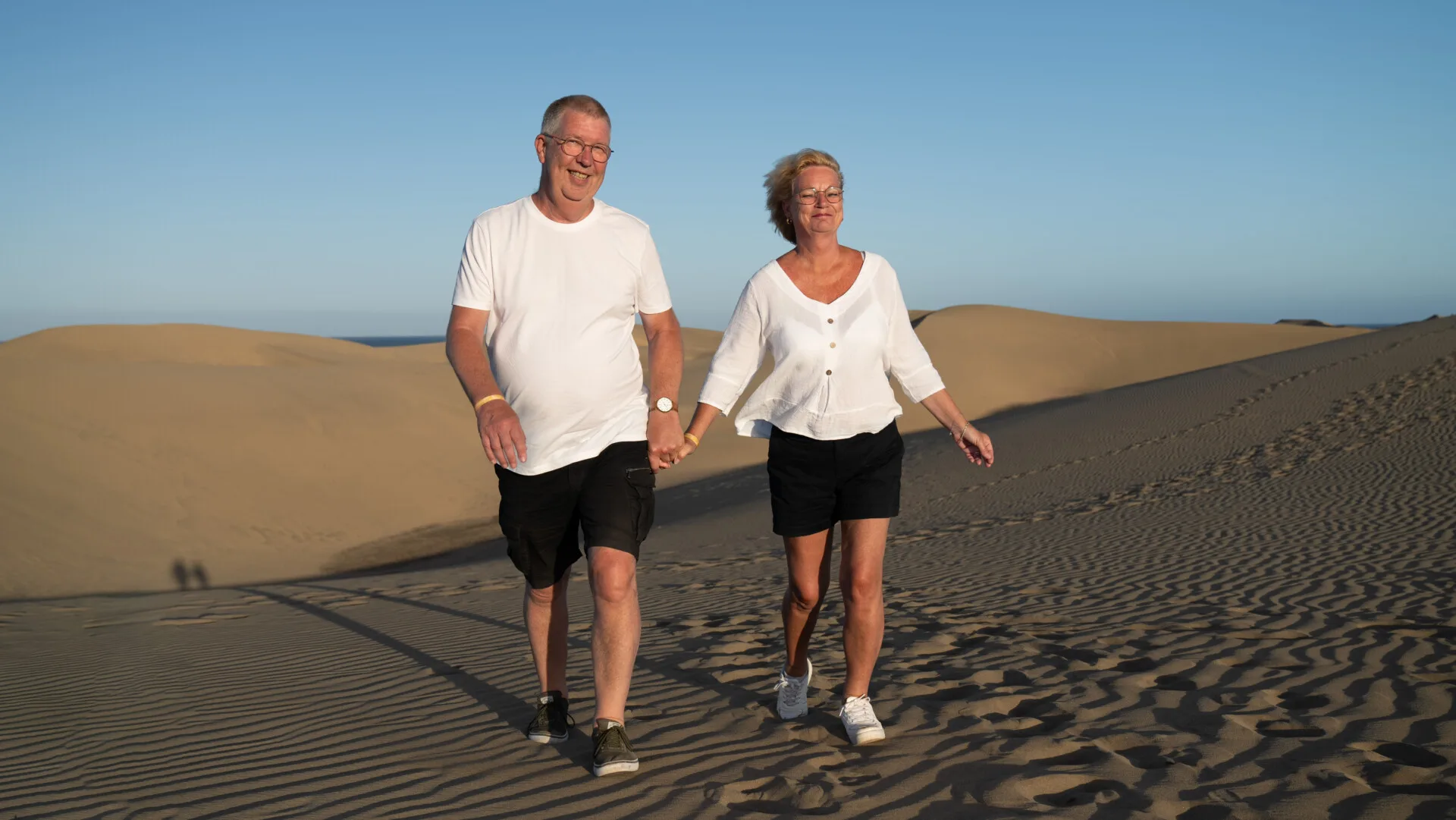 Casual couple with glasses laughing on the dunes Gran Canaria