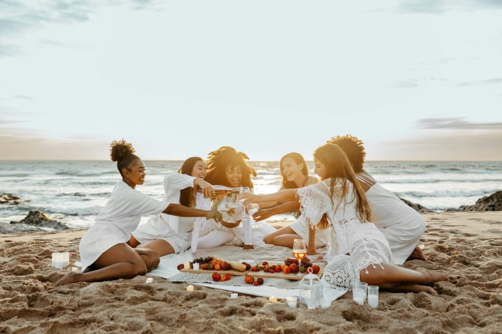 Gruppo di giovani donne che brindano con lo champagne, festeggiando l'addio al nubilato sulla spiaggia