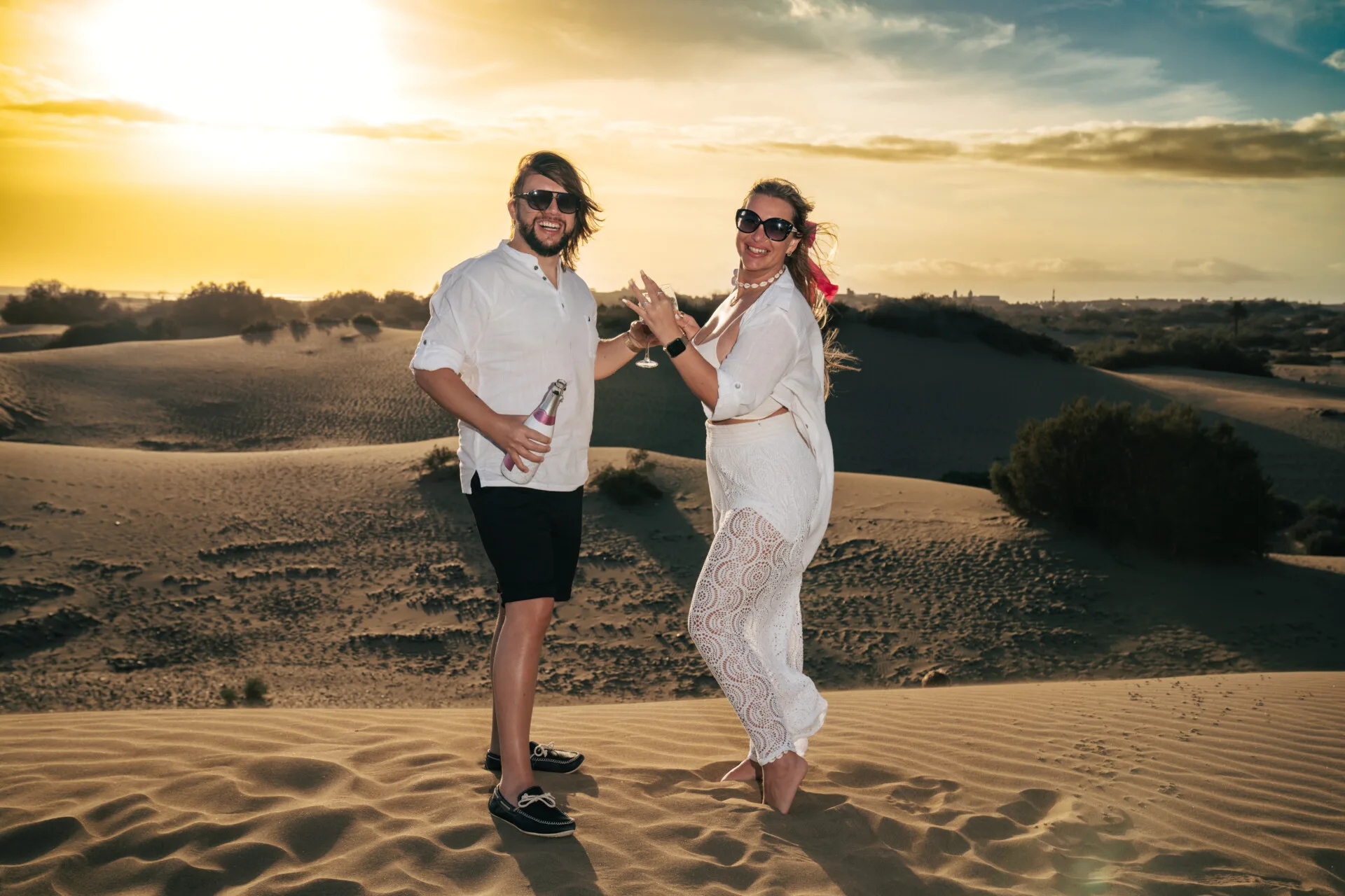 Couple celebrating proposal at sunset dunes