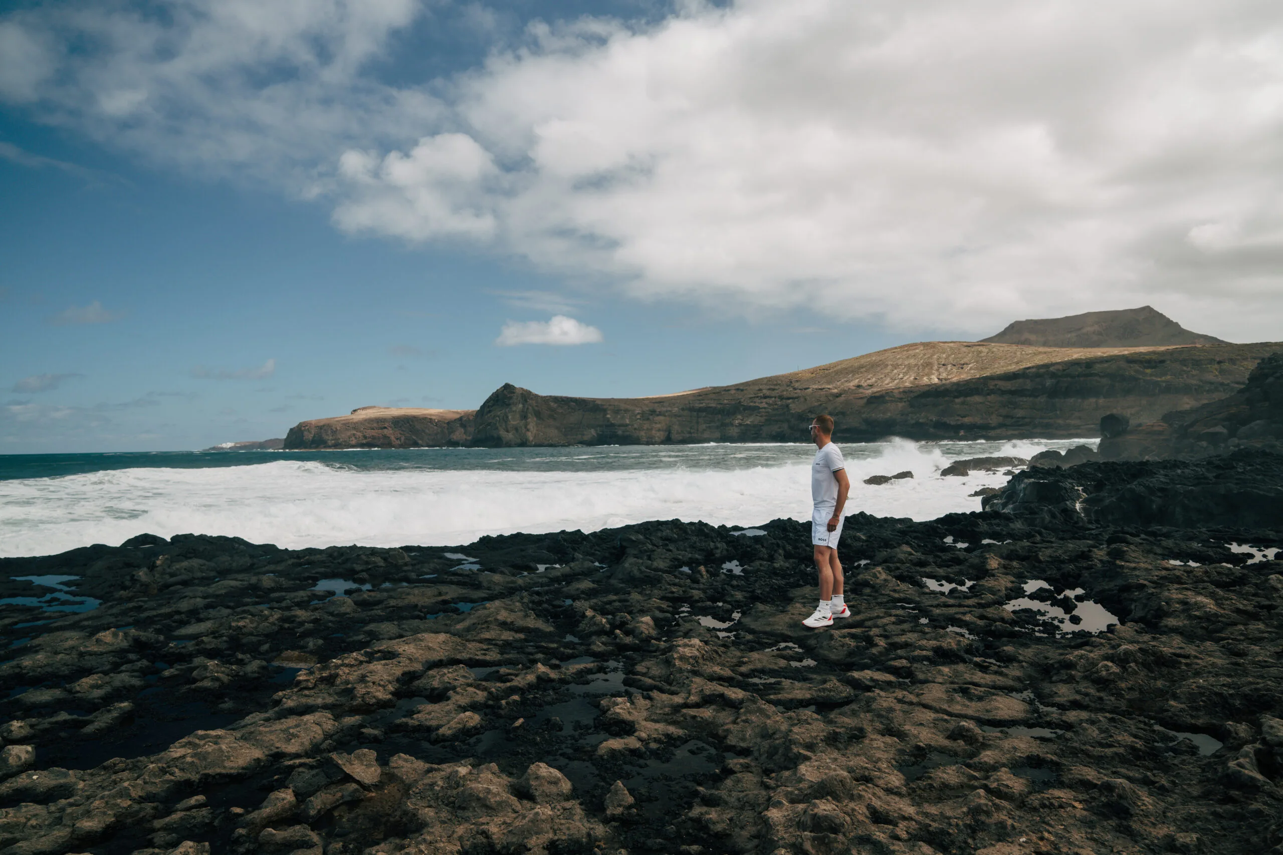 Man on black volcanic rocks Agaete coastline waves island Gran Canaria