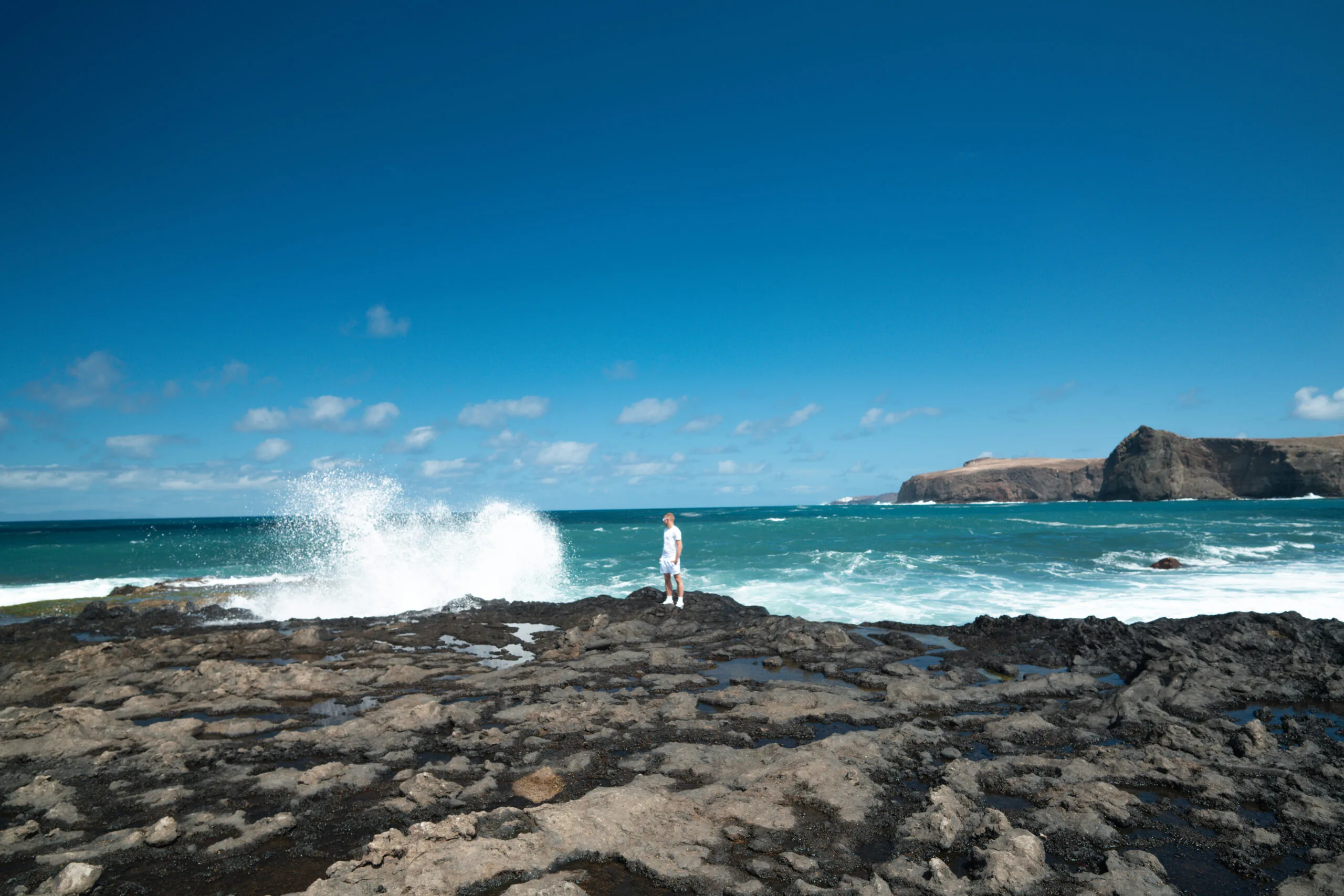 Man in white standing on rocky shore waves crashing island background Agaete Gran Canaria
